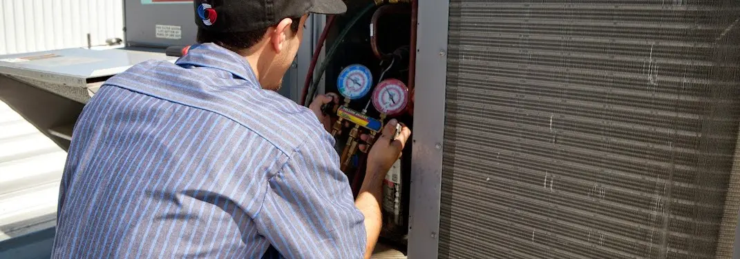 HVAC technician servicing a condenser unit in Ellsworth